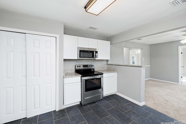 kitchen featuring kitchen peninsula, appliances with stainless steel finishes, dark carpet, ceiling fan, and white cabinets