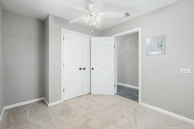 unfurnished bedroom featuring a closet, light colored carpet, ceiling fan, and electric panel