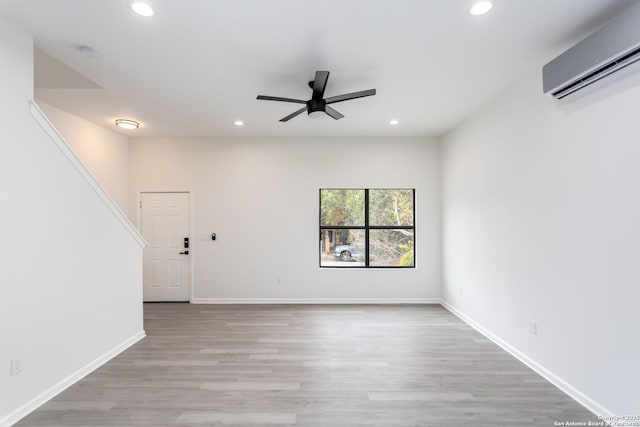 unfurnished room with ceiling fan, light hardwood / wood-style flooring, and a wall mounted air conditioner