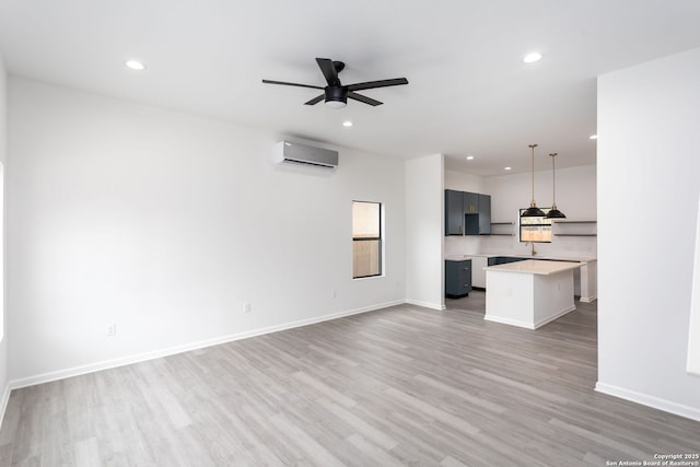 unfurnished living room featuring light wood-type flooring, a wall unit AC, and ceiling fan