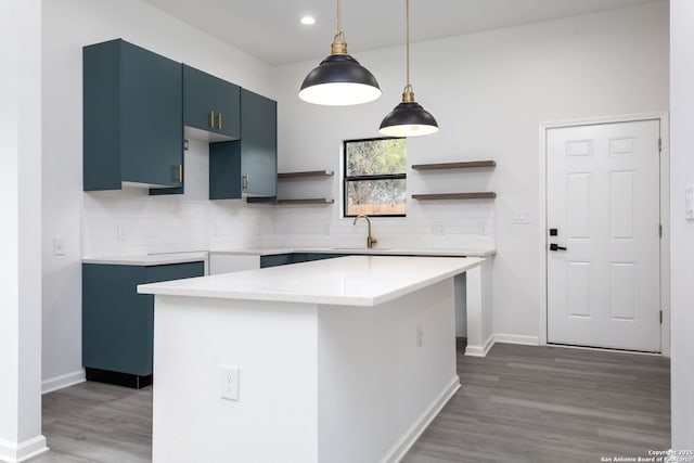 kitchen with tasteful backsplash, blue cabinets, sink, wood-type flooring, and a center island