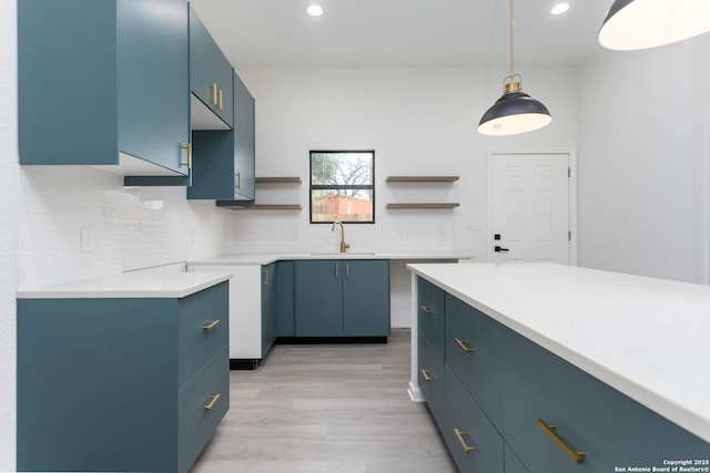 kitchen with backsplash, decorative light fixtures, blue cabinets, and sink