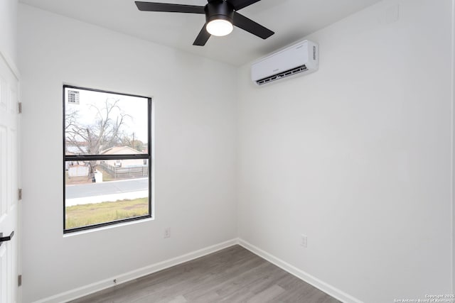 empty room with wood-type flooring, a wall unit AC, and ceiling fan