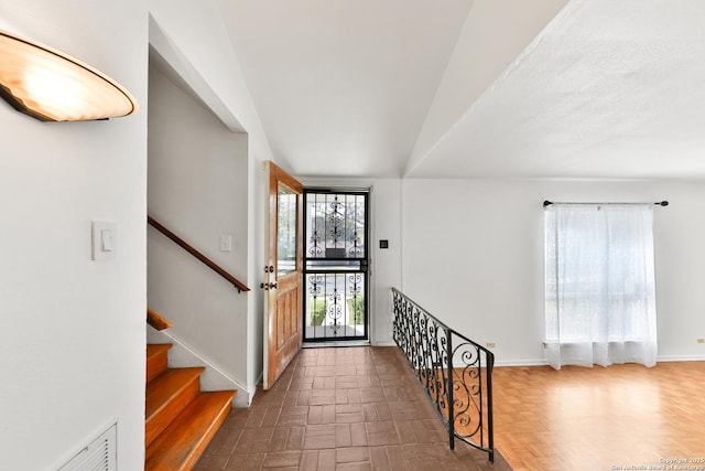 foyer featuring dark parquet flooring and lofted ceiling