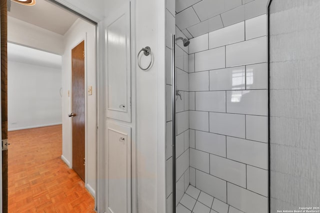 bathroom with a tile shower and parquet floors