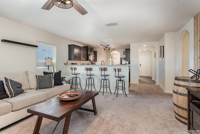 carpeted living room featuring ceiling fan and sink