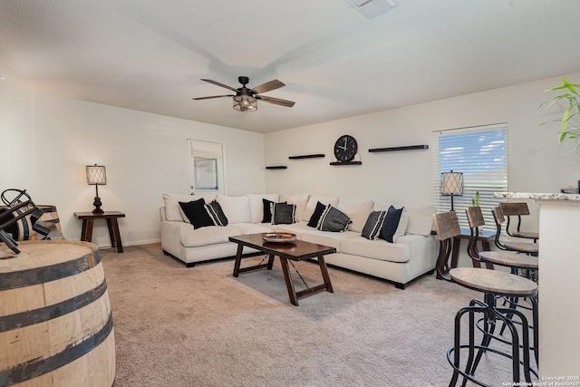 living room with a textured ceiling, light colored carpet, and ceiling fan