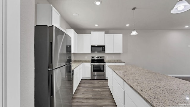 kitchen featuring stainless steel appliances, white cabinetry, light stone countertops, and hanging light fixtures