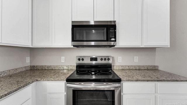 kitchen with white cabinets, stainless steel appliances, and light stone counters