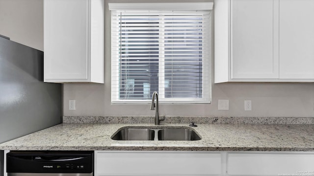 kitchen featuring sink, black dishwasher, white cabinetry, and light stone counters