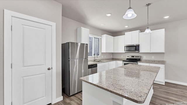 kitchen with a kitchen island, white cabinets, appliances with stainless steel finishes, and hanging light fixtures