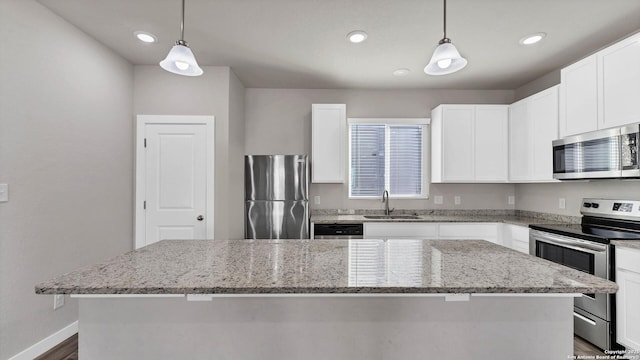 kitchen featuring light stone countertops, a center island, stainless steel appliances, white cabinets, and sink