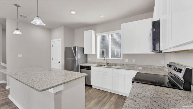 kitchen featuring appliances with stainless steel finishes, hanging light fixtures, a center island, sink, and white cabinetry