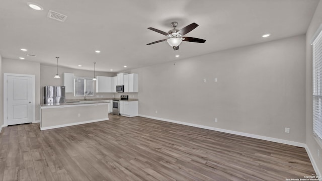 unfurnished living room featuring light hardwood / wood-style floors, ceiling fan, and sink