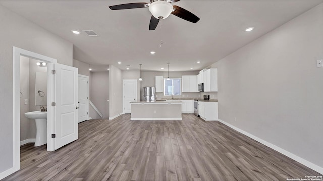 unfurnished living room with sink, ceiling fan, and light hardwood / wood-style floors