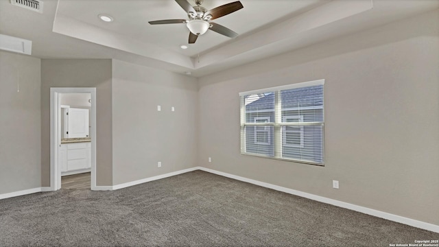 carpeted spare room with ceiling fan and a raised ceiling