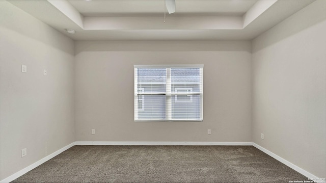 carpeted spare room featuring a raised ceiling and ceiling fan