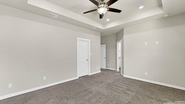 carpeted spare room with ceiling fan and a raised ceiling