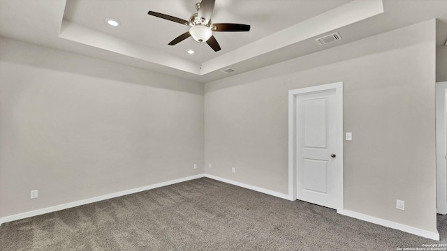 carpeted empty room featuring ceiling fan and a tray ceiling