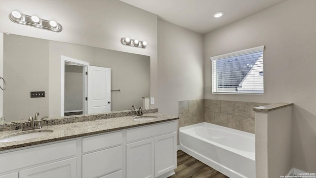 bathroom with wood-type flooring, vanity, and a tub to relax in