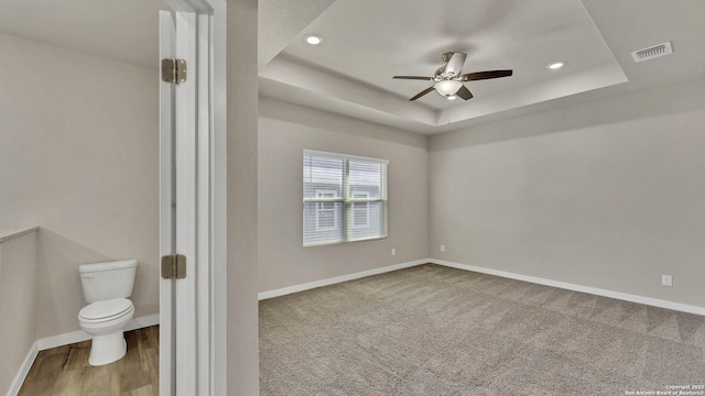 empty room featuring a raised ceiling and ceiling fan