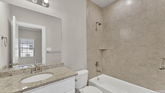 full bathroom featuring tiled shower / bath, vanity, and toilet