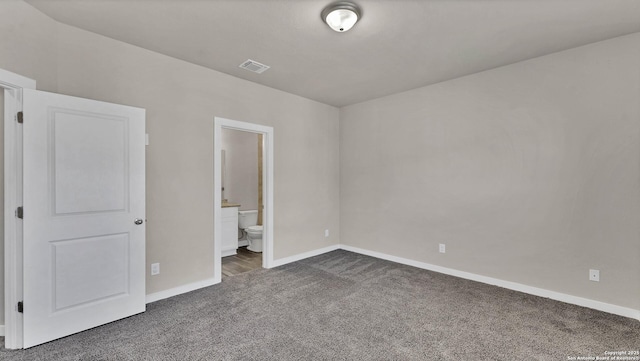 unfurnished bedroom featuring ensuite bathroom and dark carpet