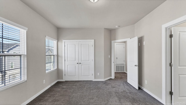 unfurnished bedroom with a closet and dark carpet