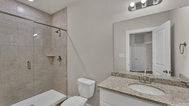 bathroom with toilet, a shower with door, and vanity