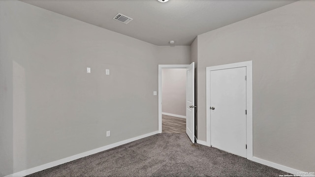 unfurnished room with dark colored carpet