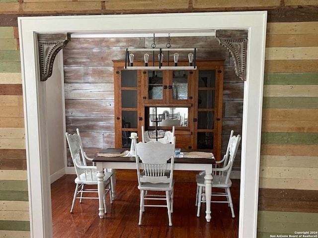 dining space with wood-type flooring and wood walls