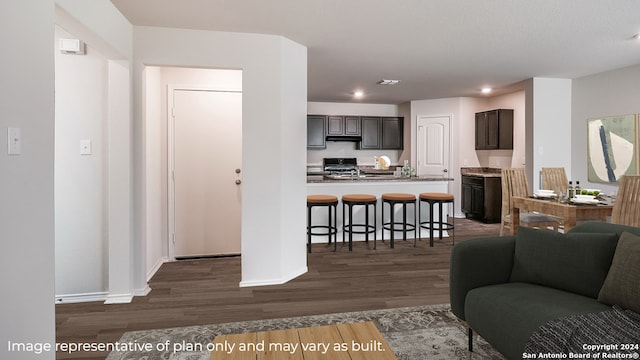 kitchen featuring dark brown cabinetry, a breakfast bar, dark wood-type flooring, and black gas range oven