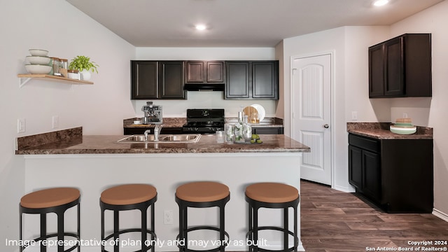 kitchen featuring kitchen peninsula, black range with gas cooktop, dark brown cabinets, sink, and dark hardwood / wood-style floors