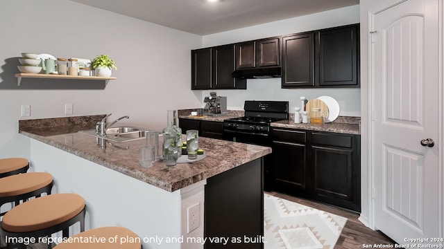 kitchen with sink, black gas range oven, kitchen peninsula, wood-type flooring, and a breakfast bar area