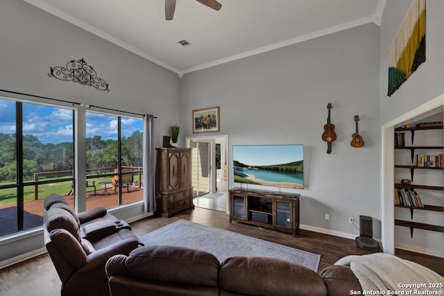 living room with ceiling fan, a towering ceiling, wood-type flooring, and ornamental molding