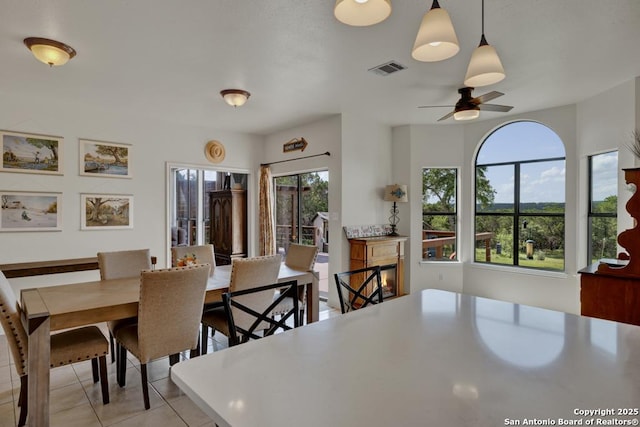 dining room featuring ceiling fan, a wealth of natural light, and light tile patterned flooring