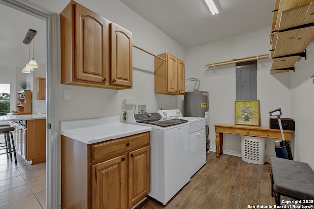 laundry room featuring electric panel, washer and clothes dryer, cabinets, and light hardwood / wood-style floors