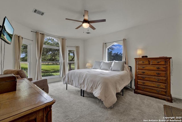 bedroom featuring ceiling fan, light carpet, and multiple windows