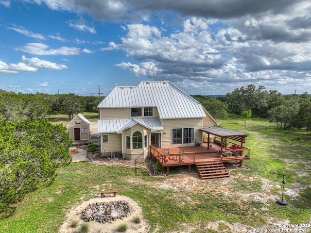 rear view of property featuring a lawn, a wooden deck, and a fire pit