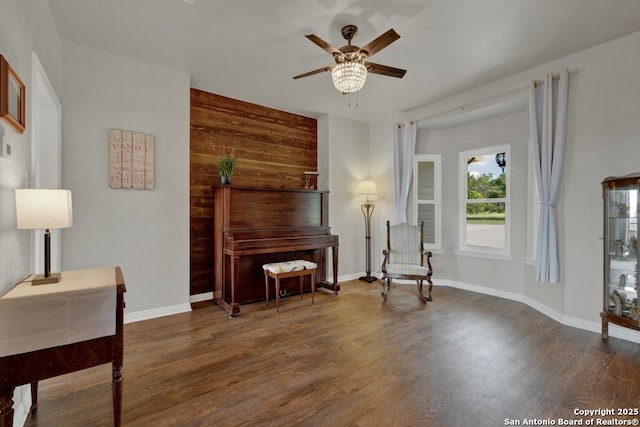 sitting room featuring wood walls, dark hardwood / wood-style floors, and ceiling fan