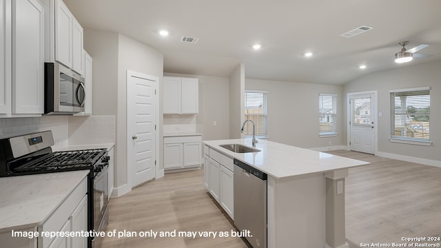 kitchen featuring white cabinets, sink, stainless steel appliances, and a kitchen island with sink
