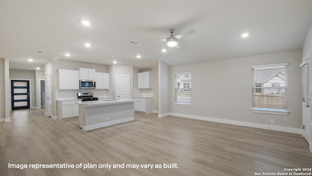kitchen with sink, light hardwood / wood-style flooring, a kitchen island with sink, white cabinets, and appliances with stainless steel finishes