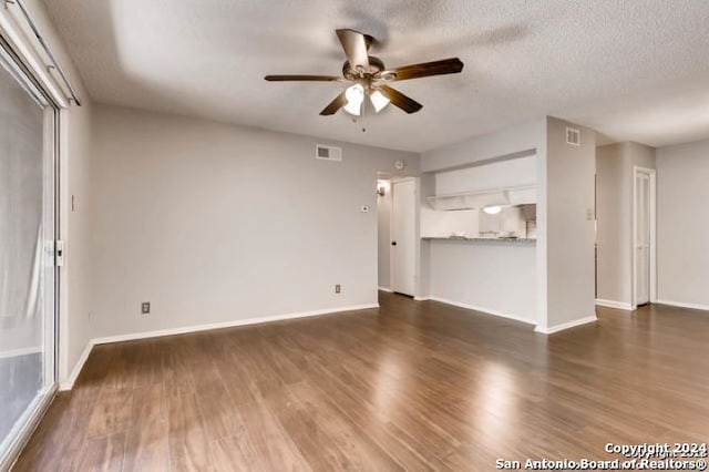 unfurnished living room featuring a textured ceiling, ceiling fan, and dark wood-type flooring