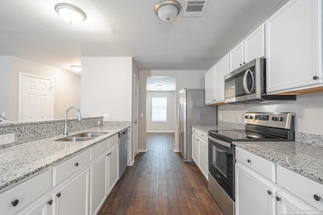 kitchen featuring appliances with stainless steel finishes, light stone counters, white cabinetry, and sink