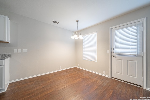 unfurnished dining area with dark hardwood / wood-style flooring and a chandelier