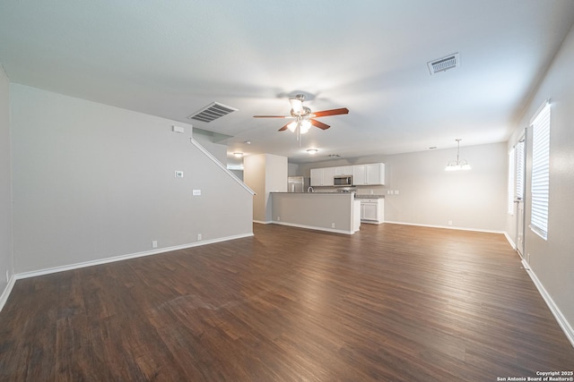 unfurnished living room featuring ceiling fan with notable chandelier and dark hardwood / wood-style flooring