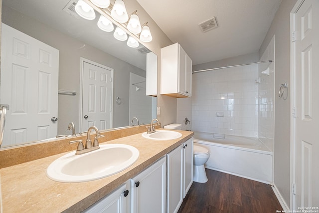 full bathroom featuring vanity, tiled shower / bath combo, hardwood / wood-style flooring, and toilet