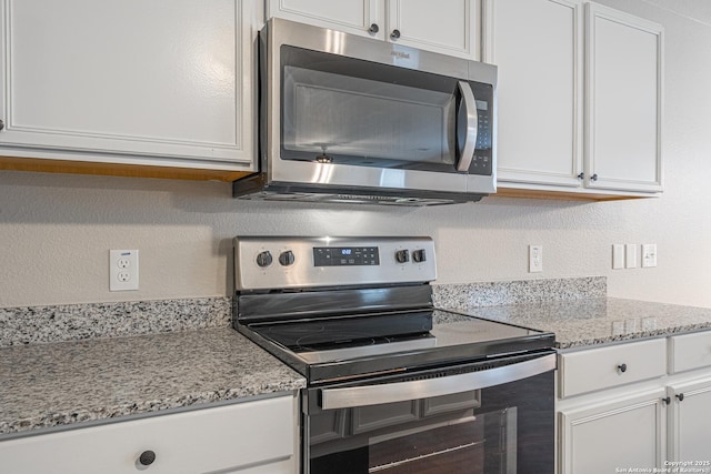 kitchen featuring appliances with stainless steel finishes, white cabinetry, and light stone counters