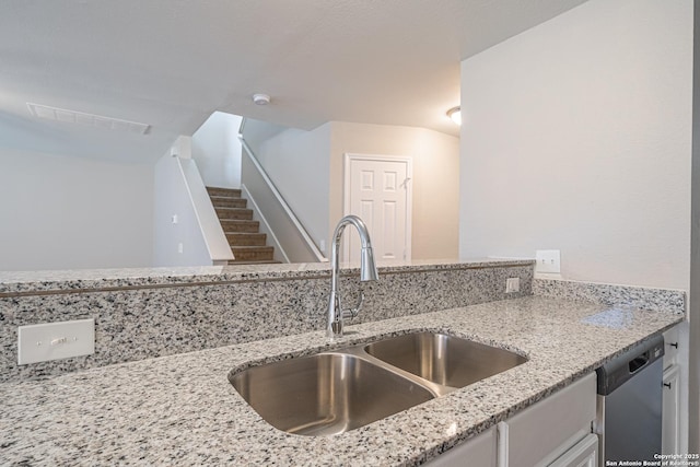 kitchen with light stone counters, stainless steel dishwasher, and sink