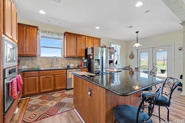 kitchen featuring french doors, sink, decorative light fixtures, a kitchen island, and stainless steel appliances